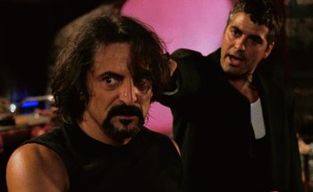 Movie still from “From Dusk Till Dawn” (1996), directed by Robert Rodriguez – A man with long hair is getting his hair combed by another man; Close Up shot, Over the shoulder angle