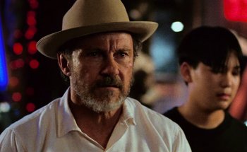 Movie still from “From Dusk Till Dawn” (1996), directed by Robert Rodriguez – An older man wearing a hat and a white shirt; Close Up shot, Over the shoulder angle