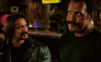 Movie still from “From Dusk Till Dawn” (1996), directed by Robert Rodriguez – Two men in leather jackets are standing in front of a bar; Close Up shot, Over the shoulder angle