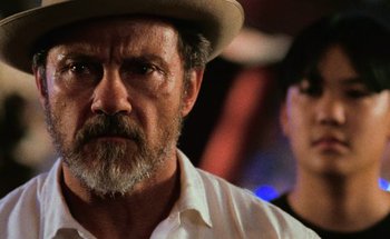 Movie still from “From Dusk Till Dawn” (1996), directed by Robert Rodriguez – A man with a beard and a hat is looking at the camera; Close Up shot, Low angle