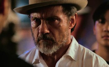 Movie still from “From Dusk Till Dawn” (1996), directed by Robert Rodriguez – An older man wearing a white shirt and a brown hat; Close Up shot, Over the shoulder angle