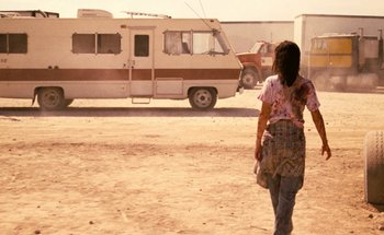 Movie still from “From Dusk Till Dawn” (1996), directed by Robert Rodriguez – A woman walking in front of an rv in the desert; Wide shot, Low angle