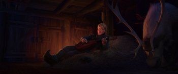 Movie still from “Frozen” (2013), directed by Jennifer Lee – A man laying on top of a pile of hay holding a guitar; Wide shot, High angle