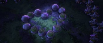 Movie still from “Frozen” (2013), directed by Jennifer Lee – A group of purple balls sitting in the middle of a green field; Extreme Wide shot, Overhead angle