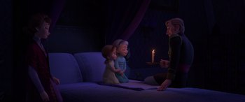 Movie still from “Frozen II” (2019), directed by Jennifer Lee – Two little girls sitting next to a man in front of a lit candle; Wide shot, High angle