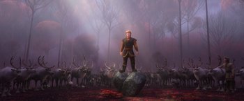 Movie still from “Frozen II” (2019), directed by Jennifer Lee – A man standing on top of a rock in the middle of a forest; Wide shot, High angle