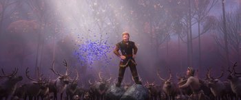 Movie still from “Frozen II” (2019), directed by Jennifer Lee – A man standing on top of a rock in front of a herd of deer; Wide shot, Low angle