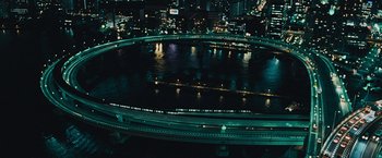 Movie still from “Furious 7” (2015), directed by James Wan – An aerial view of a city at night with lights; Extreme Wide shot, High angle