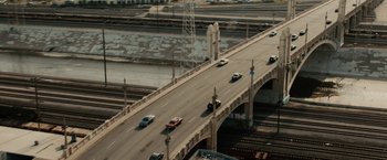 Movie still from “Furious 7” (2015), directed by James Wan – Cars are driving on a bridge over a river; Extreme Wide shot, High angle