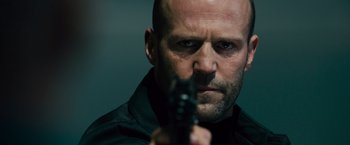 Movie still from “Furious 7” (2015), directed by James Wan – A man with a gun in his hand and wearing a black shirt; Close Up shot, Low angle