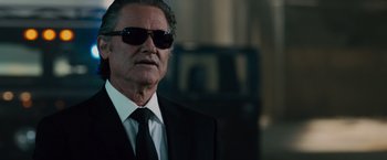 Movie still from “Furious 7” (2015), directed by James Wan – An older man in a suit and sunglasses; Close Up shot, Low angle
