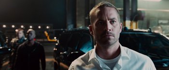 Movie still from “Furious 7” (2015), directed by James Wan – A person wearing a white shirt; Close Up shot, Over the shoulder angle