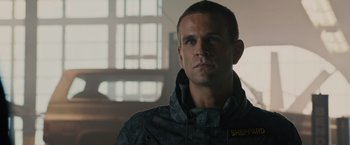 Movie still from “Furious 7” (2015), directed by James Wan – A person wearing a jacket in a room; Close Up shot, Low angle
