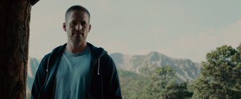 Movie still from “Furious 7” (2015), directed by James Wan – A person standing in front of a mountain range; Close Up shot, Over the shoulder angle