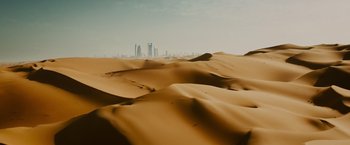 Movie still from “Furious 7” (2015), directed by James Wan – A view of a city from the sand dunes in the desert; Extreme Wide shot, High angle