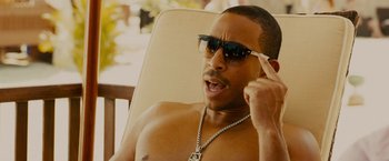 Movie still from “Furious 7” (2015), directed by James Wan – A man wearing sunglasses while sitting in a chair; Close Up shot, High angle