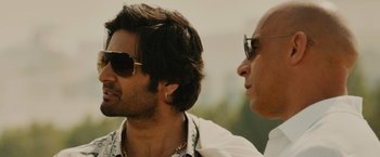 Movie still from “Furious 7” (2015), directed by James Wan – Two men wearing sunglasses are looking at each other; Close Up shot, Over the shoulder angle