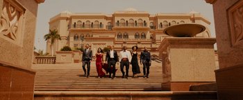 Movie still from “Furious 7” (2015), directed by James Wan – A group of people standing on some steps in front of a building; Wide shot, Low angle