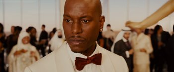 Movie still from “Furious 7” (2015), directed by James Wan – A person wearing a bow tie; Close Up shot, Over the shoulder angle