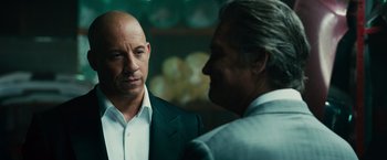 Movie still from “Furious 7” (2015), directed by James Wan – A man in a suit and tie talking to another man in a suit and tie; Close Up shot, Over the shoulder angle