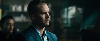Movie still from “Furious 7” (2015), directed by James Wan – A person wearing a suit and tie; Close Up shot, Over the shoulder angle