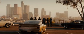 Movie still from “Furious 7” (2015), directed by James Wan – A group of people standing around a car on the side of the road; Wide shot, High angle
