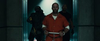 Movie still from “Furious 7” (2015), directed by James Wan – A group of men standing next to each other in a room; Medium shot, Low angle