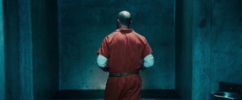 Movie still from “Furious 7” (2015), directed by James Wan – A man in a red prison uniform standing in front of a blue wall; Medium shot, Low angle
