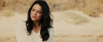 Movie still from “Furious 7” (2015), directed by James Wan – A woman with long black curly hair looking to her left; Close Up shot, Over the shoulder angle