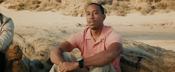 Movie still from “Furious 7” (2015), directed by James Wan – A man sitting on the ground with his hands on his knees; Close Up shot, High angle