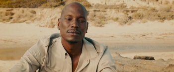 Movie still from “Furious 7” (2015), directed by James Wan – A person sitting on a beach; Close Up shot, High angle