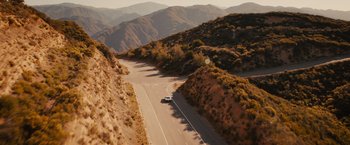 Movie still from “Furious 7” (2015), directed by James Wan – An aerial view of a car driving down a mountain road; Extreme Wide shot, High angle