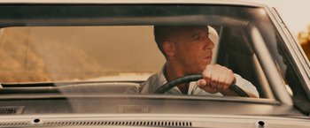 Movie still from “Furious 7” (2015), directed by James Wan – A man is driving a car in the street; Close Up shot, Over the shoulder angle