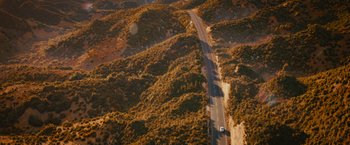 Movie still from “Furious 7” (2015), directed by James Wan – An aerial view of a road going through the hills; Extreme Wide shot, High angle