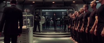 Movie still from “G.I. Joe: The Rise of Cobra” (2009), directed by Stephen Sommers – A group of men in black suits standing in front of a building; Wide shot, Low angle