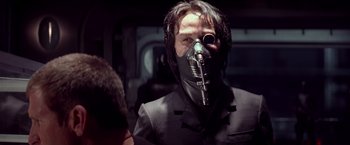 Movie still from “G.I. Joe: The Rise of Cobra” (2009), directed by Stephen Sommers – A man wearing a suit and a gas mask; Close Up shot, Over the shoulder angle