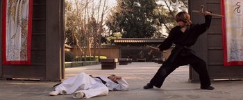 Movie still from “G.I. Joe: The Rise of Cobra” (2009), directed by Stephen Sommers – A man in a black shirt and a white shirt is on the ground; Wide shot, Over the shoulder angle