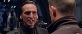 Movie still from “G.I. Joe: The Rise of Cobra” (2009), directed by Stephen Sommers – A man wearing a suit and tie talking to another man; Close Up shot, Over the shoulder angle