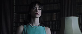 Movie still from “All the Money in the World” (2017), directed by Ridley Scott – A woman in a green dress with a pearl necklace in front of a book shelf; Close Up shot, Low angle