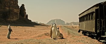 Movie still from “All the Money in the World” (2017), directed by Ridley Scott – Two people sitting on the side of a dirt road in the middle of the desert; Extreme Wide shot, Low angle