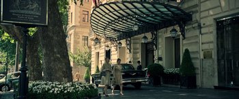 Movie still from “All the Money in the World” (2017), directed by Ridley Scott – Two women walk down the street in front of an old car; Wide shot, Low angle
