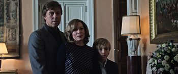 Movie still from “All the Money in the World” (2017), directed by Ridley Scott – Two adults and a child posing for a picture; Medium shot, Low angle