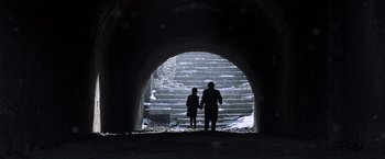 Movie still from “All the Money in the World” (2017), directed by Ridley Scott – A man and a woman standing in front of a tunnel; Extreme Wide shot, Low angle