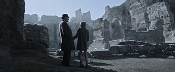 Movie still from “All the Money in the World” (2017), directed by Ridley Scott – A man and a woman holding hands while standing in front of ruins; Wide shot, Low angle