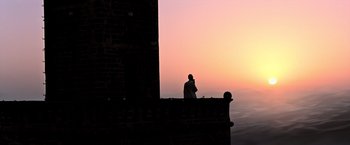Movie still from “All the Money in the World” (2017), directed by Ridley Scott – A man standing on a ledge looking out at the sunset; Extreme Wide shot, Low angle