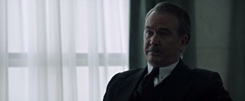 Movie still from “All the Money in the World” (2017), directed by Ridley Scott – An older man wearing a suit and tie looking off into the distance; Close Up shot, Low angle