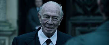 Movie still from “All the Money in the World” (2017), directed by Ridley Scott – An older man in a suit and tie; Close Up shot, Over the shoulder angle