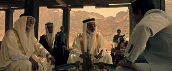 Movie still from “All the Money in the World” (2017), directed by Ridley Scott – An old man in a white robe sitting at a table with other people; Medium shot, Over the shoulder angle