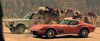 Movie still from “All the Money in the World” (2017), directed by Ridley Scott – A couple of camels riding on the back of a red car; Wide shot, Low angle