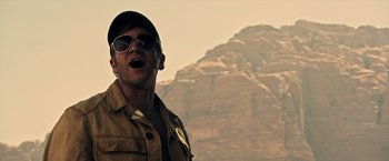 Movie still from “All the Money in the World” (2017), directed by Ridley Scott – A man in a hat and sunglasses is standing in front of a mountain; Close Up shot, Low angle